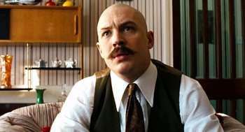 Movie still from “Bronson” (2008), directed by Nicolas Winding Refn – A bald man with a mustache wearing a vest and a tie; Close Up shot, Low angle