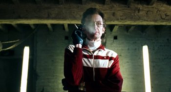 Movie still from “Bronson” (2008), directed by Nicolas Winding Refn – A man in a red and white striped jacket holding a cell phone to his ear; Medium shot, Low angle