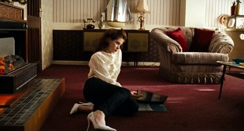 Movie still from “Bronson” (2008), directed by Nicolas Winding Refn – A woman sitting on the ground looking at a picture; Medium shot, High angle