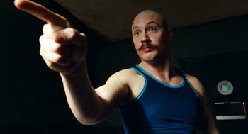 Movie still from “Bronson” (2008), directed by Nicolas Winding Refn – A bald man with a mustache is pointing; Close Up shot, Low angle