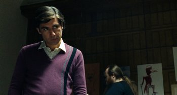 Movie still from “Bronson” (2008), directed by Nicolas Winding Refn – A man in a purple sweater standing next to a woman; Medium shot, Over the shoulder angle