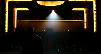Movie still from “Bronson” (2008), directed by Nicolas Winding Refn – A man standing in front of an audience at night; Extreme Wide shot, Low angle