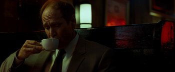 Movie still from “Brooklyn's Finest” (2009), directed by Antoine Fuqua – A man in a suit and tie drinking a cup of coffee; Medium shot, Low angle
