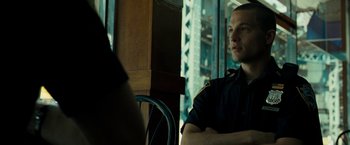 Movie still from “Brooklyn's Finest” (2009), directed by Antoine Fuqua – A police officer sitting at a table with his arms crossed; Medium shot, Low angle