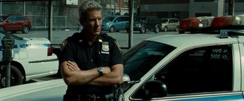 Movie still from “Brooklyn's Finest” (2009), directed by Antoine Fuqua – A police officer standing in front of a police car; Medium shot, Over the shoulder angle