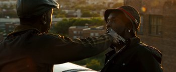 Movie still from “Brooklyn's Finest” (2009), directed by Antoine Fuqua – A man in a hat is holding a gun to his mouth; Close Up shot, Over the shoulder angle