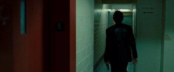 Movie still from “Brooklyn's Finest” (2009), directed by Antoine Fuqua – A person walking down a hall way with a umbrella; Medium shot, Over the shoulder angle