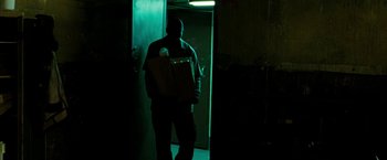 Movie still from “Brooklyn's Finest” (2009), directed by Antoine Fuqua – A man holding a box in a dark room; Medium shot, Low angle