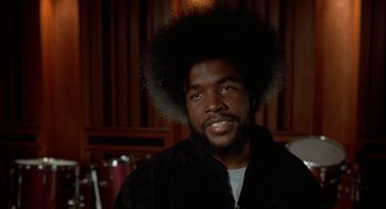 Movie still from “Brown Sugar” (2002), directed by Rick Famuyiwa – A man with a beard and a large afro; Close Up shot, Over the shoulder angle