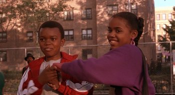 Movie still from “Brown Sugar” (2002), directed by Rick Famuyiwa – Two young children standing next to each other in front of a building; Medium shot, High angle
