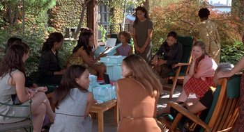 Movie still from “Brown Sugar” (2002), directed by Rick Famuyiwa – A group of people sitting around a table with boxes; Wide shot, High angle