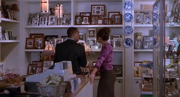 Movie still from “Brown Sugar” (2002), directed by Rick Famuyiwa – A man and a woman standing in front of a wall of pictures; Medium shot, Over the shoulder angle