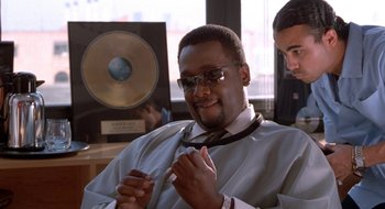Movie still from “Brown Sugar” (2002), directed by Rick Famuyiwa – A man sitting in front of a record player; Medium shot, Over the shoulder angle