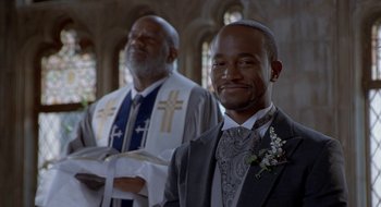 Movie still from “Brown Sugar” (2002), directed by Rick Famuyiwa – A man in a suit and tie standing in front of a priest; Close Up shot, Low angle