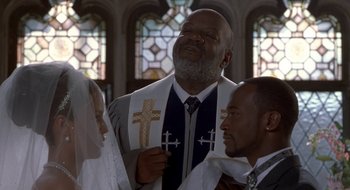 Movie still from “Brown Sugar” (2002), directed by Rick Famuyiwa – A man wearing a priest's outfit in front of two other men; Medium shot, Low angle