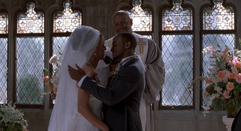Movie still from “Brown Sugar” (2002), directed by Rick Famuyiwa – A bride and groom kissing in front of a priest in a church; Medium shot, Low angle