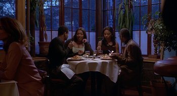 Movie still from “Brown Sugar” (2002), directed by Rick Famuyiwa – A group of people sitting around a table eating; Wide shot, High angle