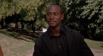 Movie still from “Brown Sugar” (2002), directed by Rick Famuyiwa – A man in a black shirt and black jacket is smiling; Close Up shot, Over the shoulder angle