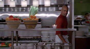 Movie still from “Brown Sugar” (2002), directed by Rick Famuyiwa – A man standing in front of an oven in a kitchen; Medium shot, Over the shoulder angle