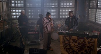 Movie still from “Brown Sugar” (2002), directed by Rick Famuyiwa – A man standing next to another man with a microphone; Wide shot, High angle