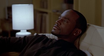 Movie still from “Brown Sugar” (2002), directed by Rick Famuyiwa – A man sitting on a couch in a living room; Close Up shot, High angle