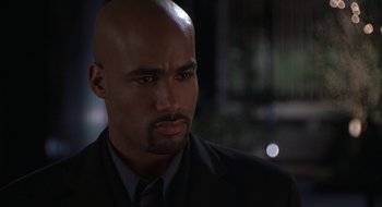 Movie still from “Brown Sugar” (2002), directed by Rick Famuyiwa – A bald man in a suit and tie looking to his left; Close Up shot, High angle