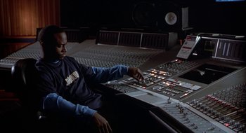 Movie still from “Brown Sugar” (2002), directed by Rick Famuyiwa – A man sitting in front of a sound board; Medium shot, High angle