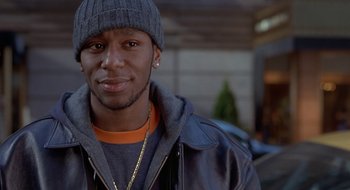 Movie still from “Brown Sugar” (2002), directed by Rick Famuyiwa – A person wearing a jacket and a hat; Close Up shot, Over the shoulder angle