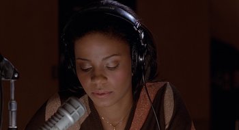 Movie still from “Brown Sugar” (2002), directed by Rick Famuyiwa – A woman wearing headphones and singing into a microphone; Close Up shot, High angle