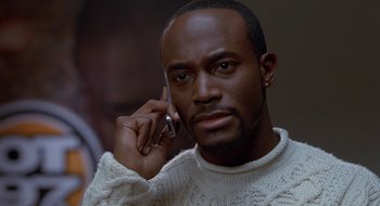 Movie still from “Brown Sugar” (2002), directed by Rick Famuyiwa – A man in a white sweater talking on a cell phone; Close Up shot, Low angle