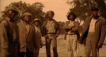 Movie still from “Buck and the Preacher” (1972), directed by Joseph Sargent – A group of men standing next to each other on top of a field; Medium shot, Low angle