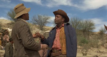 Movie still from “Buck and the Preacher” (1972), directed by Joseph Sargent – A man in a cowboy hat is holding a hammer; Medium shot, Over the shoulder angle