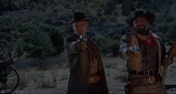 Movie still from “Buck and the Preacher” (1972), directed by Joseph Sargent – A man in a hat and a suit is pointing a gun; Medium shot, Low angle