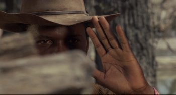 Movie still from “Buck and the Preacher” (1972), directed by Joseph Sargent – A man in a hat is holding his hand up to his face; Close Up shot, Over the shoulder angle