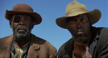 Movie still from “Buck and the Preacher” (1972), directed by Joseph Sargent – A couple of men standing next to each other in a field; Close Up shot, Low angle