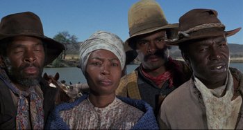 Movie still from “Buck and the Preacher” (1972), directed by Joseph Sargent – A group of people standing next to each other near a body of water; Medium shot, Low angle