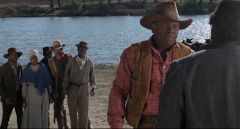 Movie still from “Buck and the Preacher” (1972), directed by Joseph Sargent – A group of men walking along the shore of a body of water; Medium shot, Over the shoulder angle