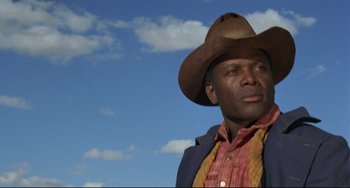 Movie still from “Buck and the Preacher” (1972), directed by Joseph Sargent – A man wearing a cowboy hat standing in front of a blue sky; Close Up shot, Low angle