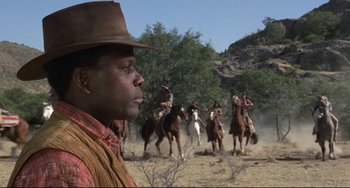 Movie still from “Buck and the Preacher” (1972), directed by Joseph Sargent – A group of men on horseback riding across a field; Medium shot, Low angle
