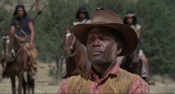 Movie still from “Buck and the Preacher” (1972), directed by Joseph Sargent – A man wearing a cowboy hat while standing next to a horse; Close Up shot, Low angle
