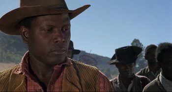 Movie still from “Buck and the Preacher” (1972), directed by Joseph Sargent – A man wearing a cowboy hat in a field with other men; Close Up shot, Low angle