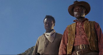 Movie still from “Buck and the Preacher” (1972), directed by Joseph Sargent – Two men standing next to each other on a hill; Medium shot, Low angle