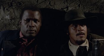 Movie still from “Buck and the Preacher” (1972), directed by Joseph Sargent – Two men standing next to each other in front of a brick wall; Close Up shot, Low angle