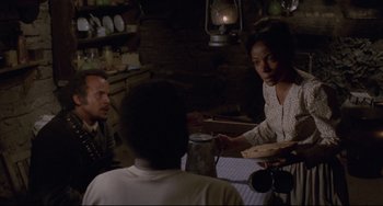 Movie still from “Buck and the Preacher” (1972), directed by Joseph Sargent – Three people sitting at a table in front of a lamp; Medium shot, Over the shoulder angle