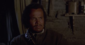 Movie still from “Buck and the Preacher” (1972), directed by Joseph Sargent – A man with a beard is talking on a phone; Close Up shot, Over the shoulder angle