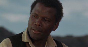 Movie still from “Buck and the Preacher” (1972), directed by Joseph Sargent – A person wearing a vest looking at the camera; Close Up shot, Low angle