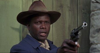 Movie still from “Buck and the Preacher” (1972), directed by Joseph Sargent – A man holding a gun while wearing a cowboy hat; Close Up shot, Low angle