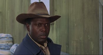 Movie still from “Buck and the Preacher” (1972), directed by Joseph Sargent – A man wearing a cowboy hat and a blue suit; Close Up shot, Low angle