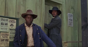 Movie still from “Buck and the Preacher” (1972), directed by Joseph Sargent – A couple of men standing next to each other; Medium shot, Low angle