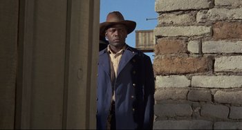 Movie still from “Buck and the Preacher” (1972), directed by Joseph Sargent – A man wearing a hat and a blue jacket; Medium shot, Low angle